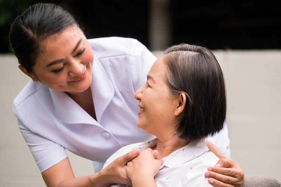 Beautiful nurse taking care of female patient at the hospital park